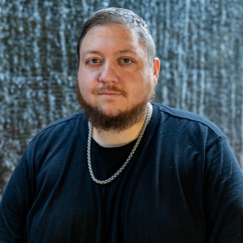 male with chain necklace in front of wall of water