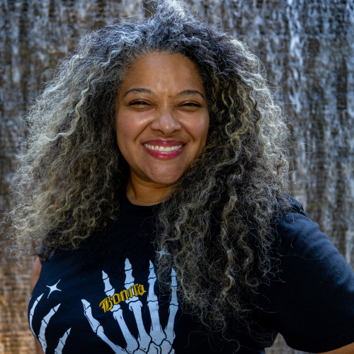 female standing in front of a wall of water flowing down smiling