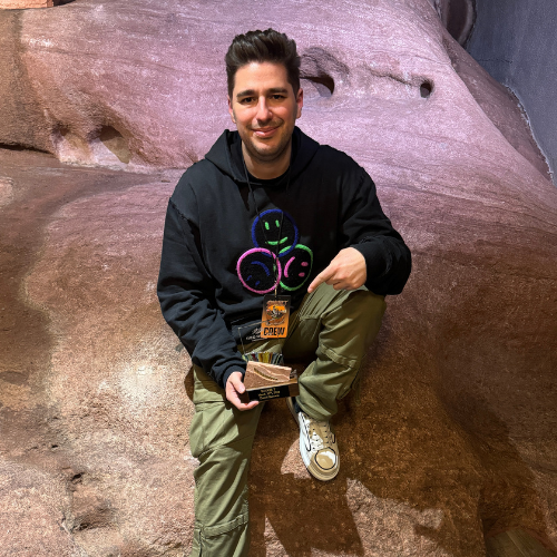 man sitting on rocks holding an award