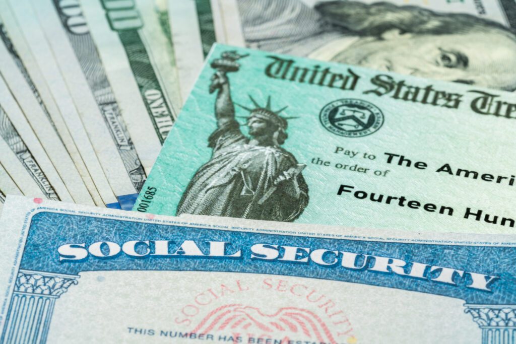 Stack of 100 dollar bills with US Treasury illustrative check and top of a social security card