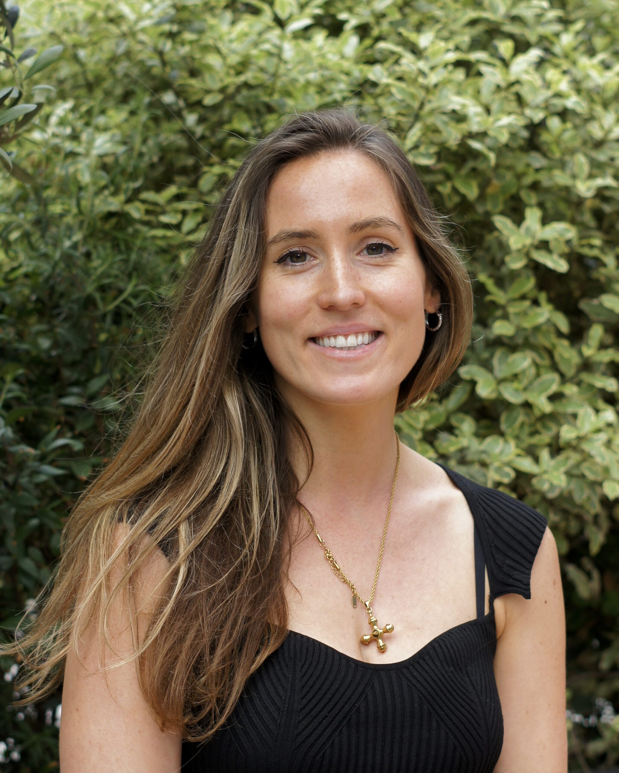 Female headshot wearing tank top standing in front of a tree